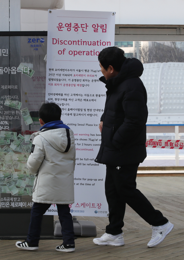 미세먼지 주의보 발령으로 서울광장 스케이트장 운영이 중단된 13일 한 가족이 운영중단 알림 안내문을 보고 있다. 연합뉴스