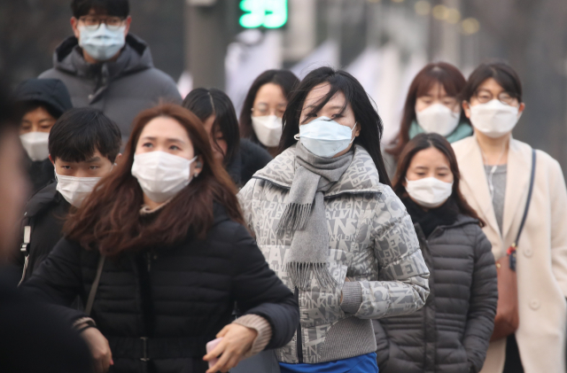 고농도 미세먼지가 기승을 부리면서 수도권을 포함한 전국 곳곳에 미세먼지 비상저감조치가 시행된 14일 오전 서울 광화문 네거리에서 출근길에 오른 시민들이 마스크를 쓰고서 횡단보도를 건너고 있다. 연합뉴스