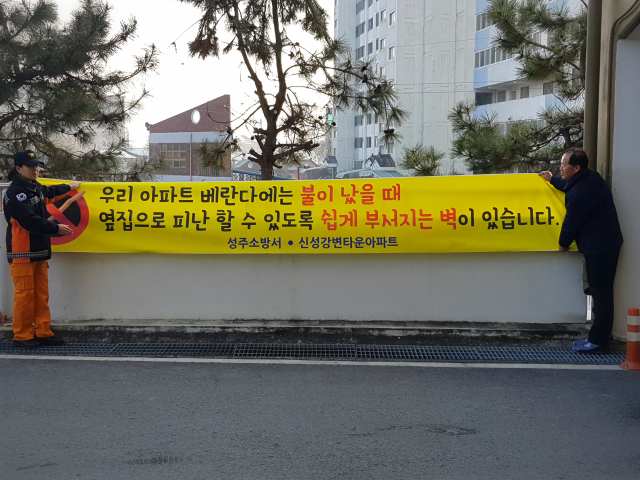 성주소방서 관계자들이 경량칸막의 중요성을 홍보하는 현수막을 부착하고 있다.