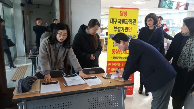 어린이과학체험관이 국립대구과학관에 건립되는 것으로 확정됐다. 달성군학부모협회가 벌이고 있는 어린이과학체험관 유치 운동에 김문오 달성군수와 주민들이 서명하고 있는 모습. 달성군학부모협회 제공