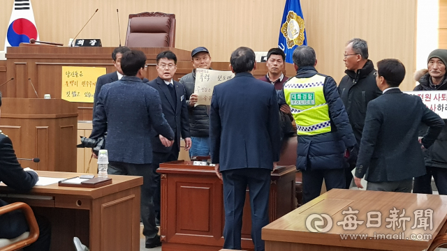 임시회 직전 군의원 전원 사퇴가 적힌 종이 팻말을 붙이려는 농민단체 회원들와 이를 말리는 군의회 직원들이 마찰을 빚자 경찰이 이들을 제지하고 있다. 윤영민 기자