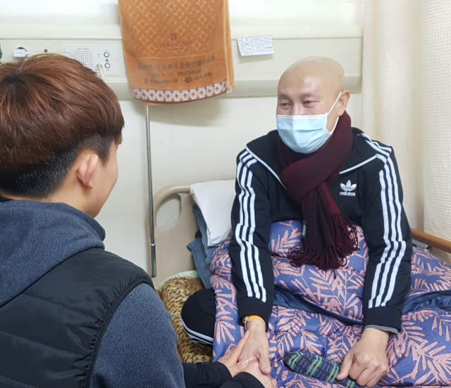 이현철(49·가명) 씨가 둘째 아들 이상현(17·가명) 군의 손을 붙잡고 있다. 이군의 치료비를 마련하다가 췌장암 판정을 받은 이씨는 극심한 생활고 속에서 하루하루 고통속에서 지내고 있다. 이주형 기자