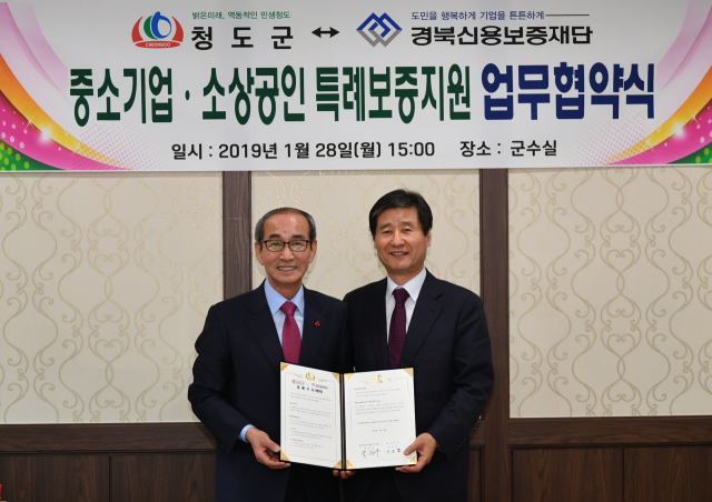 박진우 경북신용보증재단 이사장(오른쪽)과 이승율 청도군수가 중소기업·소상공인·농업인 특례보증 지원을 위한 양해각서를 체결하고 있다. 경북신용보증재단 제공