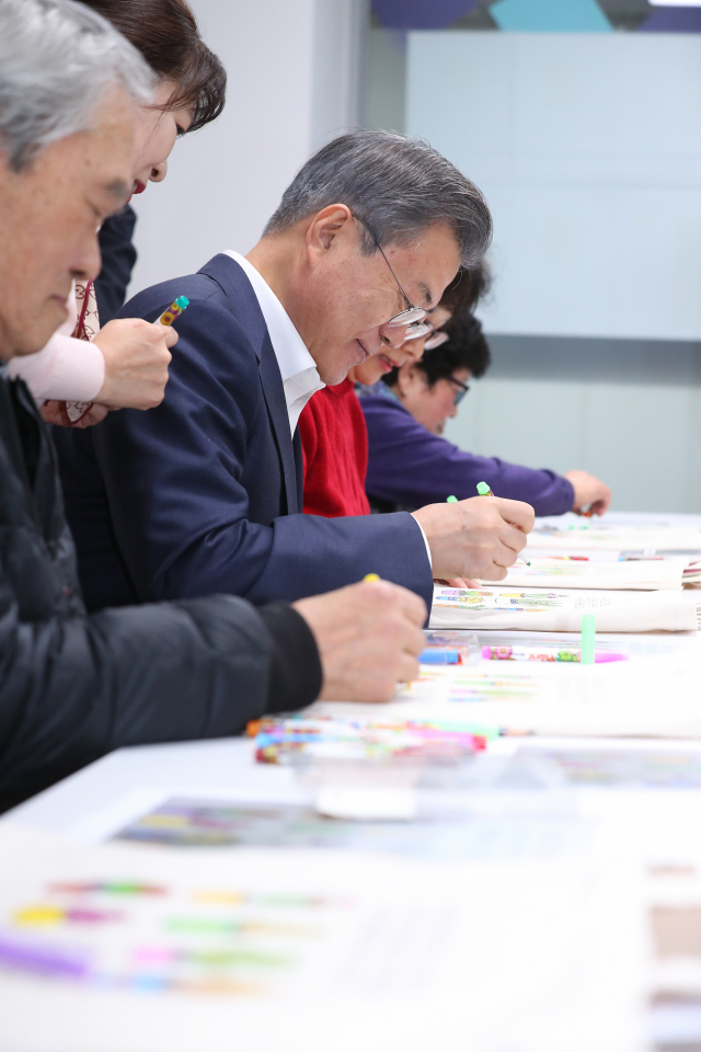 문재인 대통령이 19일 오후 서울 노원구 월계문화복지센터에서 포용국가 사회정책 대국민 보고를 하기에 앞서 어르신 복지 프로그램 현장을 찾아 어르신들과 함께 에코백 색칠을 하고 있다. 연합뉴스