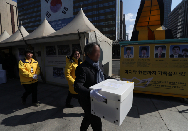 17일 서울 광화문광장 세월호 천막에서 열린 이안식에서 4·16 세월호 참사 유족들이 희생자 영정을 옮기고 있다. 세월호 천막은 2014년 7월 처음 설치된 후 약 4년 8개월 만에 유가족 측의 자진철거 의사에 따라 18일 모두 철거될 예정이다. 연합뉴스 #세월호 천막 #세월호 영정 #분향소