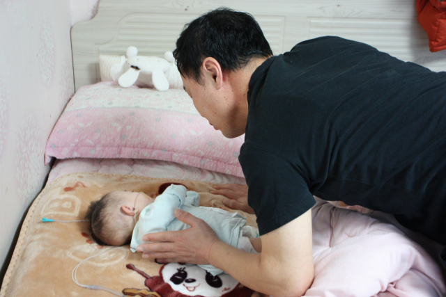 서동진(48·가명)씨가 폐렴을 앓고 있는 서대현(1· 가명)군을 보살피고 있다. 서 씨는 다운증후군을 가지고 대현군이 잘 커나갈 수 있을지 하루하루 걱정에 잠 못 이루고 있다. 이주형 기자