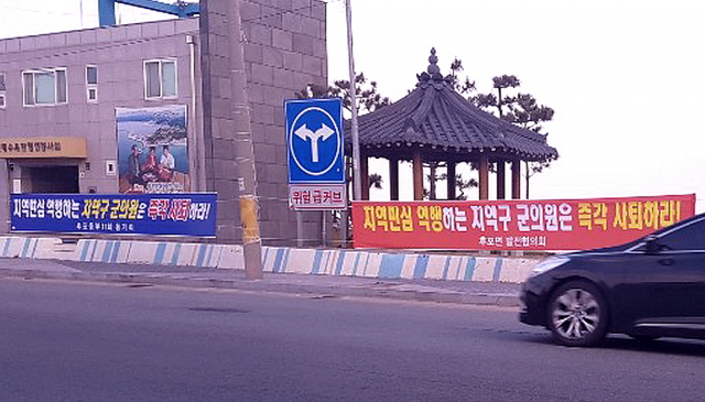 울진군 후포면 해안도로에 공영주차장 건립 예산을 부결시킨 군의원들의 사퇴를 촉구하는 현수막이 걸려 있다. 신동우 기자