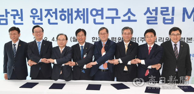 15일 부산시 기장군 고리원자력본부에서 열린 동남권 원전해체연구소 설립 업무협약식 참석자들이 손을 맞잡고 기념사진을 찍고 있다. 왼쪽부터 이선호 울주군수, 송호철 울산시장, 오거돈 부산시장, 성윤모 산업부 장관, 정재훈 한수원 사장, 강길부 국회의원, 이철우 경상북도지사, 주낙영 경주시장. 경북도 제공