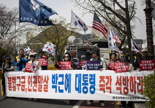 16일 오후 서울 청와대 춘추관 앞에서 열린 박근혜 전 대통령 석방 촉구 기자회견에서 태극기혁명국민운동본부 참석자들이 관련 현수막을 들고 서 있다. 연합뉴스
