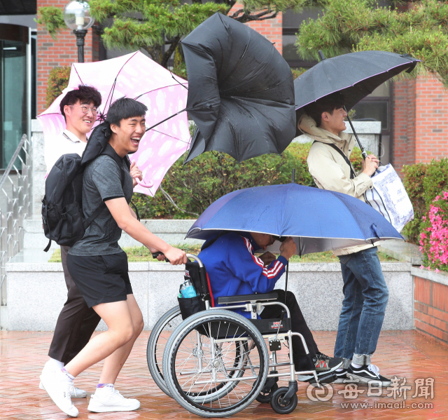 계명대학교 캠퍼스에서 우산을 받쳐 든 학생들이 바람에 우산이 뒤집어지자 웃음을 짓고 있다. 매일신문DB.