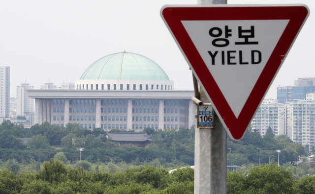 여야가 선거제·개혁법안 패스트트랙(신속처리안건) 지정 이후 사과와 법안 처리 문제 등으로 장기간 공전 중인 9일 오후 서울 여의도 서강대교에서 바라본 국회가 양보 표지판과 대비를 이루고 있다. 연합뉴스