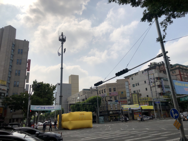 12일 오전 8시30분쯤 대구 남구 영대병원네거리 인근 CCTV 거치대에 한 남성이 올라가 인형을 매달고 시위를 하고 있다. 장성혁 기자.