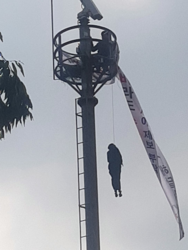 12일 오전 8시30분쯤 대구 남구 영대병원네거리 인근 CCTV 거치대에 한 남성이 올라가 인형을 매달고 시위를 하고 있다. 장성혁 기자.