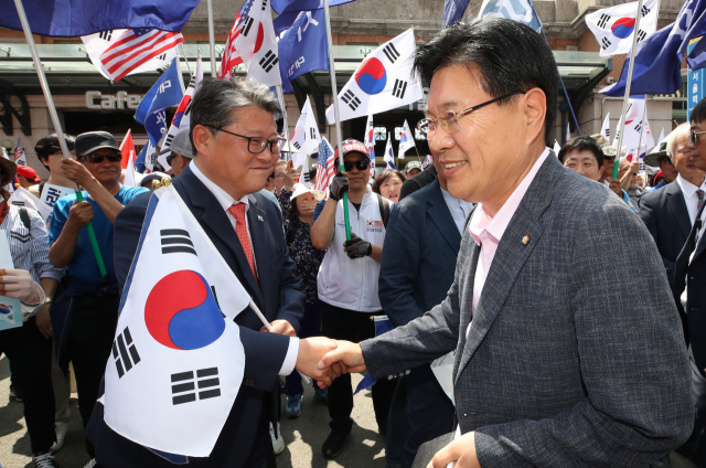 자유한국당 홍문종(오른쪽) 의원이 15일 오후 서울역 광장에서 열린 태극기집회에 참석, 조원진 대한애국당 대표와 악수하고 있다. 이 자리에서 탈당 선언을 한 홍문종 의원은 대한애국당 공동대표로 추대됐다. 연합뉴스