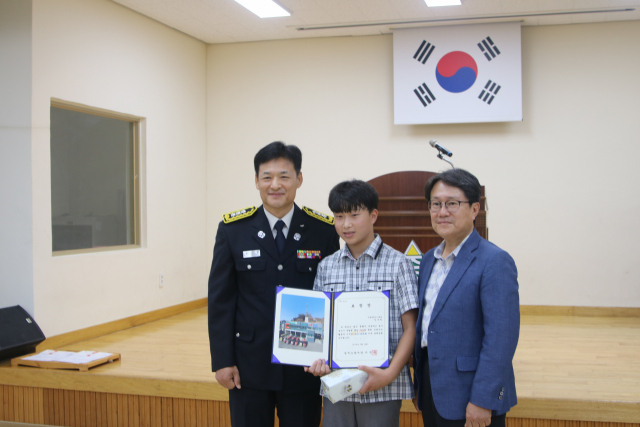성주 수륜중 한세환 군이 노인 구조 공로로 표창장을 받은 뒤 기념촬영을 하고 있다.
