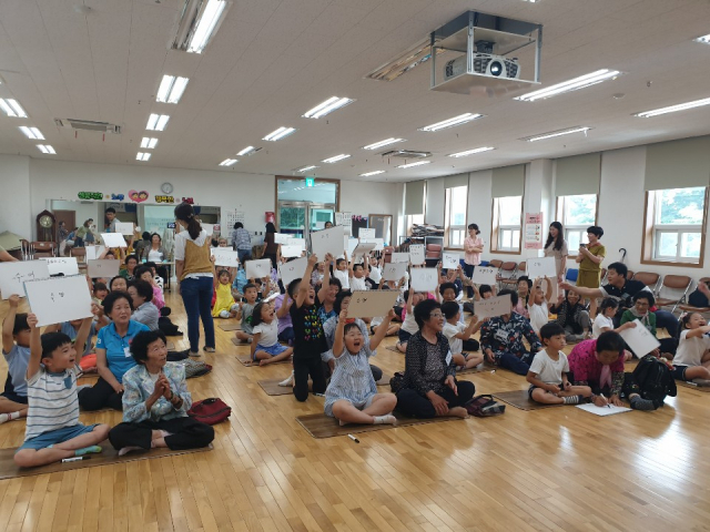 예천군 지역 어르신과 어린이 1명씩 2인 1조가 돼 물과 한글과 관련된 문제를 듣고 상의해 정답을 쓴 스케치북을 어린이들이 머리 위로 들어 올리고 있다. 예천수도관리단 제공