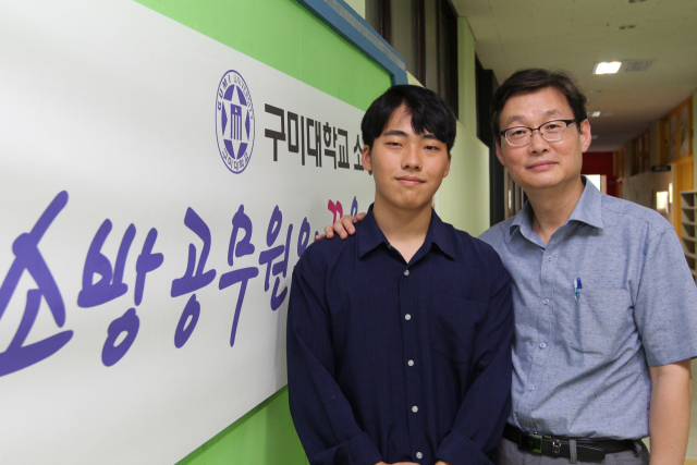 올해 경북 소방공무원 공채에 최연소로 합격한 홍원기(왼쪽·구미대 소방안전과 1년·18) 학생이 학과 실습실 앞에서 신현승 지도교수와 합격의 기쁨을 나누고 있다. 구미대 제공