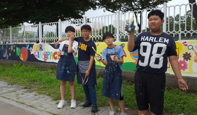 경북 성주중 학생들이 학교 담장을 벽화로 완성한 후 포즈를 취하고 있다. 성주중 제공