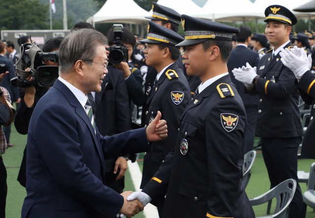 문재인 대통령이 23일 오전 충북 충주 중앙경찰학교에서 제296기 졸업생들에게 경찰관을 상징하는 흉장 수여 후 격려하고 있다. 연합뉴스