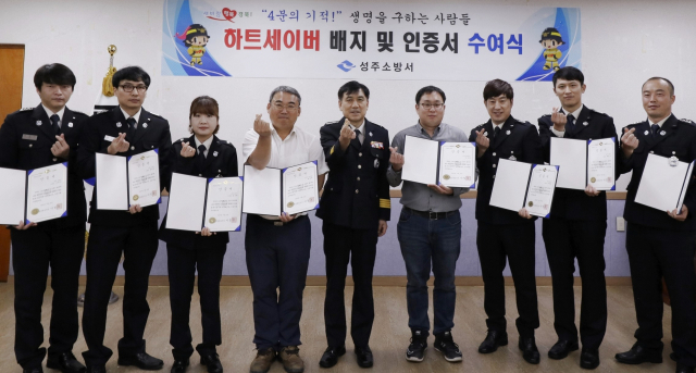 하트세이버 인증서와 배지를 받은 성주소방서 직원과 주민이 손가락 하트를 만들어 보이고 있다. 성주소방서 제공