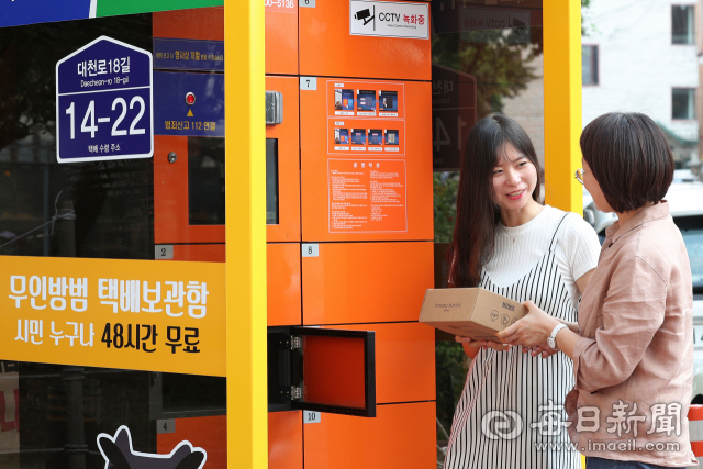 26일 오후 대구 북구 동천동에서 여성들이 택배원과 접촉 없이 안심방범택배함에 보관된 택배 물품을 받고 있다. 정운철 기자 woon@imaeil.com