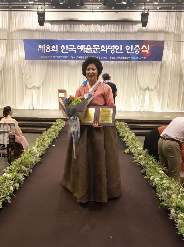 지난 26일 공예·섬유·자연염색부문 명인으로 선정된 김춘화 작가가 명인 인증서를 들어보이며 기념촬영을 하고 있다. 안동공예문화전시관 제공