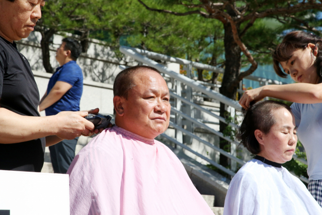 18일 경북 포항시청 앞 광장에서 김순견 전 경북도 경제부지사가 부인 박재옥씨와 함께 조국 법무부 장관 사퇴를 촉구하며 삭발을 하고 있다. 연합뉴스