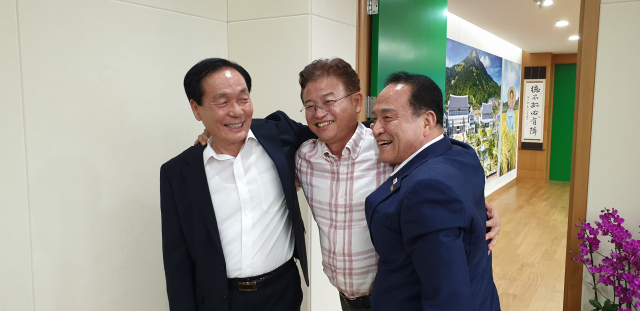 김주수 의성군수, 이철우 경북도지사, 김영만 군위군수(사진 왼쪽부터)가 21일 경북도청에서 대구경북 통합신공항 후보지 선정과 관련해 극적으로 합의안을 도출한 뒤 서로 어깨동무를 하며 환하게 웃고 있다. 권영진 대구시장은 일정상 먼저 자리를 떠났다. 임상준 기자