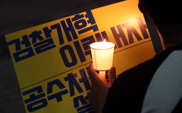 지난 16일 서울 중앙지검 앞에서 열린 검찰개혁 촉구 촛불문화제에서 한 시민이 촛불로 검찰개혁 문구를 비추고 있다. 연합뉴스