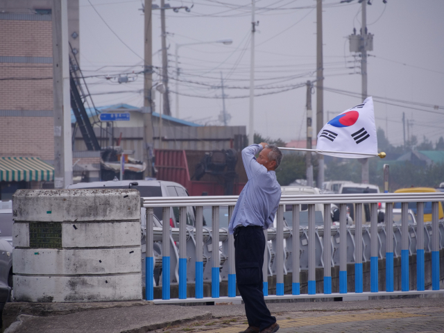 제71주년 국군의 날 기념행사가 1일 오전 대구 공군기지에서 열리는 가운데 행사 시작 전 한 시민이 공군기지 앞에서 태극기를 흔들고 있다. 안성완 영상기자