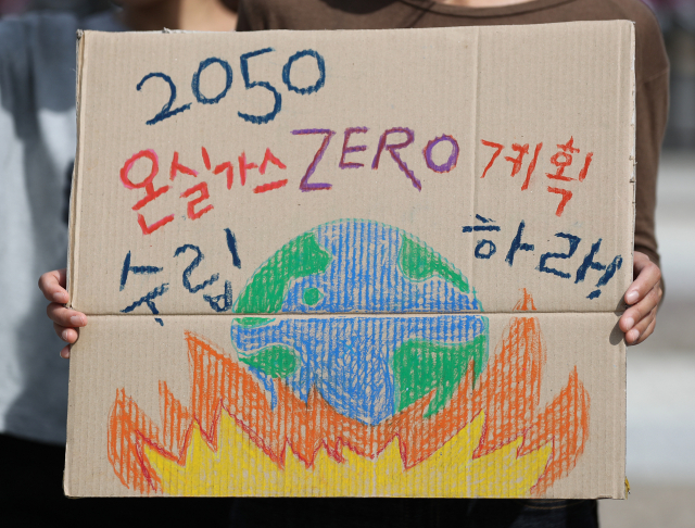 지난 25일 기후위기 비상행동 관계자가 종이상자를 재활용한 피켓을 들고 있다. 이들은 온실가스 배출제로 계획 수립 및 기후 위기 대응 범국가 기구 설치 등을 촉구했다. 연합뉴스