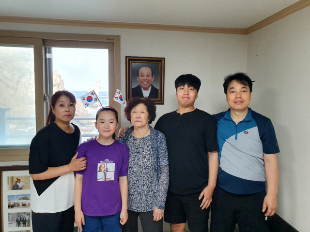 독도 유일 주민 김신열(81·가운데) 씨가 지난 8월 19일 경북 울릉군 울릉읍 독도리 서도 주민숙소에서 딸, 사위, 외손자, 외손녀와 함께 기념사진을 찍고 있다. 김 씨 뒤에는 지난해 숨진 남편 김성도 씨 사진이 걸려 있다. 연합뉴스
