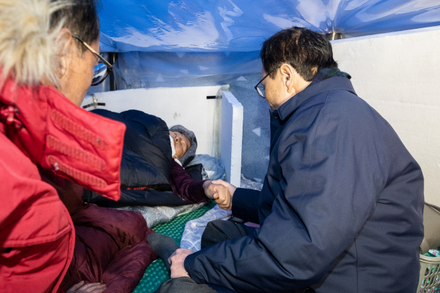 더불어민주당 이해찬 대표(오른쪽)가 25일 서울 종로구 청와대 분수대 앞에서 엿새째 단식 중인 자유한국당 황교안 대표 손을 잡고 있다. 연합뉴스