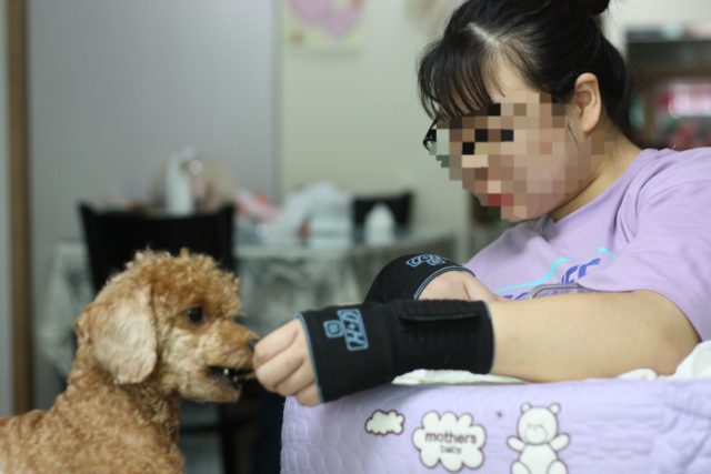 뇌병변 장애를 앓는 채린(16·가명)이가 반려견 뽀미(3·가명 )에게 간식을 주고 있다. 채린이는 뒷다리가 불편한 유기견 뽀미를 2년전부터 데려와 키우고 있다. 집에 있는 시간이 많은 이 둘은 잠도 항상 같이 자는 둘도 없는 친구다. 이주형 기자.