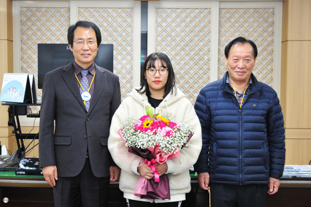 군위고 김수연(왼쪽에서 두 번째) 학생이 김기덕(맨왼쪽) 군위군수 직무대행과 심칠 군위군의회 의장으로부터 축하 꽃다발을 받고 기념사진을 찍고 있다. 군위군 제공