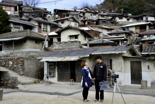 순천드라마세트장의 달동네를 배경으로 연인 한 쌍이 옛 교복 차림을 한 채 사진을 찍고 있다. 이채근 기자 mincho@imaeil.com