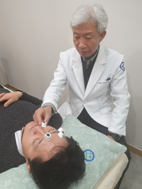 새로난한방병원 한상원 병원장이 안면신경마비 환자에게 뜸 치료를 하고 있다.