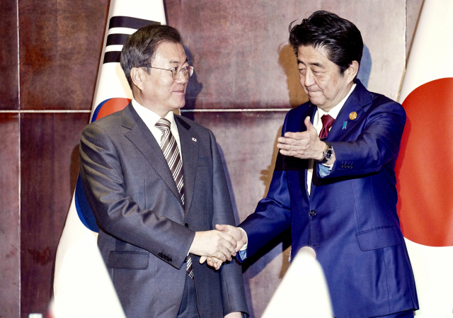 문재인 대통령과 아베 일본 총리가 24일(현지시간) 중국 쓰촨성 청두 세기성 샹그릴라호텔에서 악수하며 인사를 나누고 있다. 연합뉴스