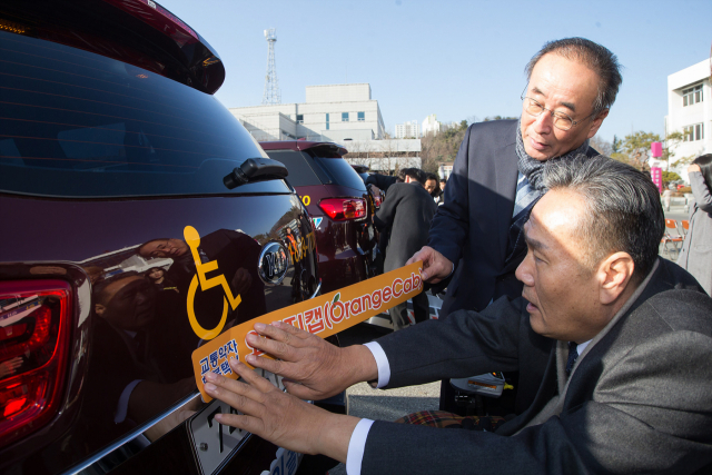 장세용(앞에서 두 번째) 구미시장이 교통약자를 위한 특별교통수단인 오랜지 캡(Orange Cab) 차량에 스티커를 부착하고 있다. 구미시 제공