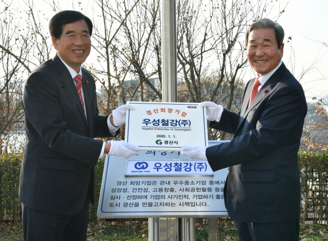 우성철강㈜ 김영만 대표(오른쪽)가 2020년 1분기 경산 희망기업으로 선정돼 2일 최영조 시장과 함께 경산시청 국기게양대 앞에서 회사기 게양 및 현판 전달식을 하고 있다.
