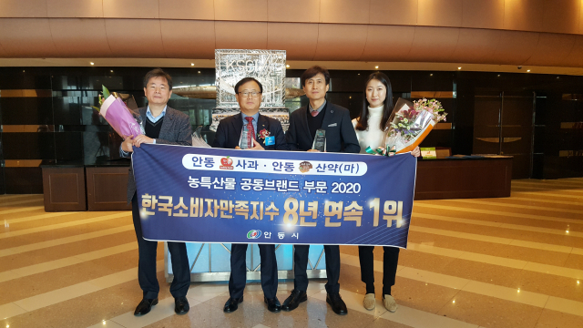 안동시 관계자들이 안동사과와 안동산약(마)의 8년 연속 소비자만족지수 1위 달성을 기념해 축하 현수막을 들고 포즈를 취하고 있다. 안동시 제공