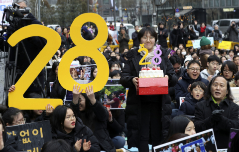 8일 서울 옛 일본대사관 앞에서 열린 1421차 일본군 성노예제 문제해결을 위한 정기 수요시위에서 한 참석자가 수요집회 28주년을 알리는 케이크를 들고 있다. 1992년 1월 8일 처음 열린 수요시위는 오늘로 28주년이 됐다. 연합뉴스