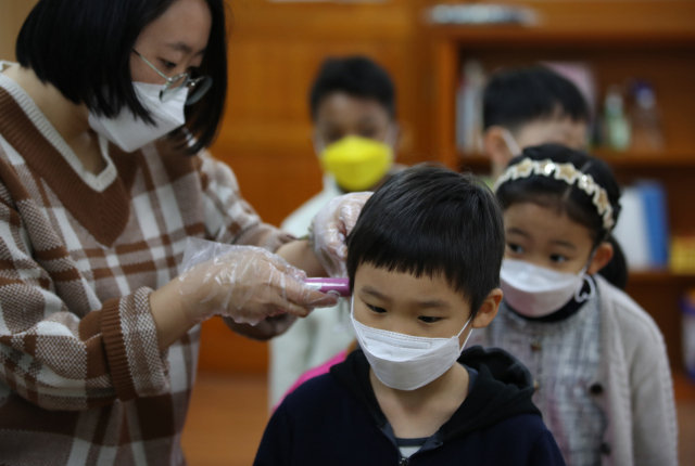 30일 오전 개학한 서울 용산초등학교에서 선생님이 신종 코로나바이러스 감염증 예방을 위해 어린이들의 체온을 측정하고 있다. 연합뉴스