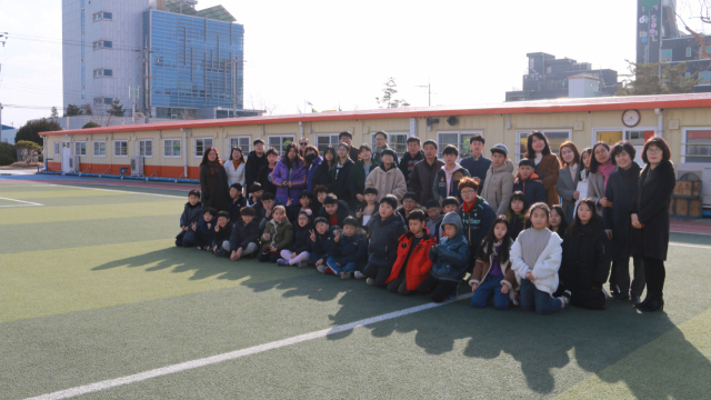 2017년 11월 포항지진 이후 흥해초교 건물이 철거되면서 운동장에 설치된 컨테이너 교실 앞에서 학생들과 교사가 사진을 찍고 있다. 포항 흥해초교 제공.