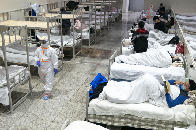 5일 중국 후베이성 우한의 한 대형 전시장을 개조한 임시병원에서 보호복을 입은 의료진이 신종 코로나바이러스 감염증 환자들 옆을 지나가고 있다 연합뉴스