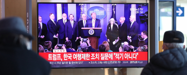27일 오전 서울역에서 시민들이 도널드 트럼프 미국 대통령의 신종 코로나바이러스 감염증(코로나19) 관련 기자회견 보도를 보고 있다. 연합뉴스
