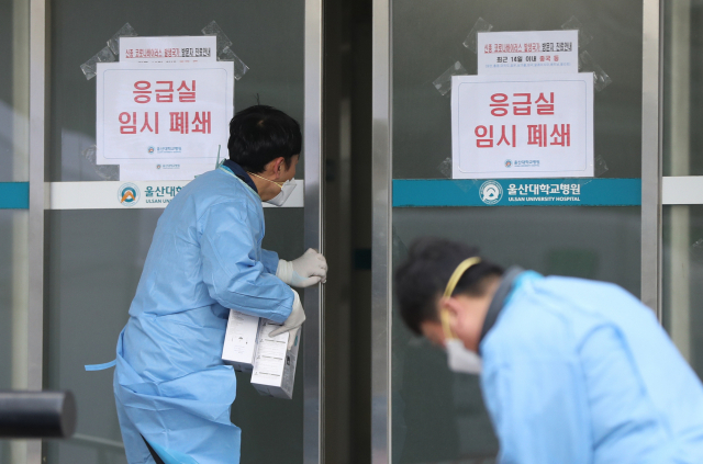 27일 오후 울산대병원 의사 1명이 신종 코로나바이러스 감염증(코로나19) 확진 판정을 받아 응급실이 폐쇄된 가운데 직원이 응급실 안으로 마스크를 전달하고 있다. 연합뉴스