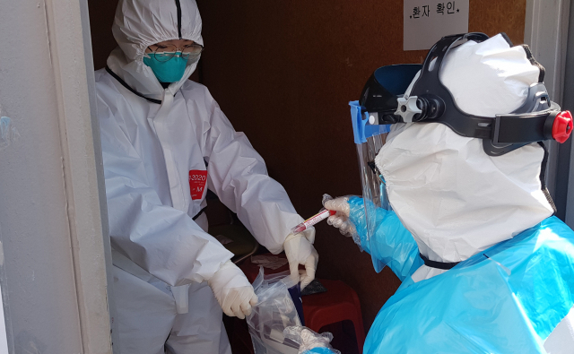 5일 오전 대구 영남대병원 드라이브 스루 선별진료소에서 간호사들이 검사 대상자들을 상대로 채취한 검체를 지퍼락에 밀봉하고 있다. 연합뉴스