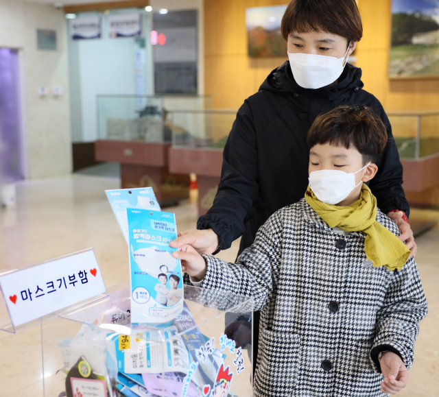 칠곡군에 사는 김여진(41) 씨와 아들 정우성(7) 군이 19일 칠곡군청 로비에 마련된 마스크 기부함에 마스크를 넣고 있다. 칠곡군 제공