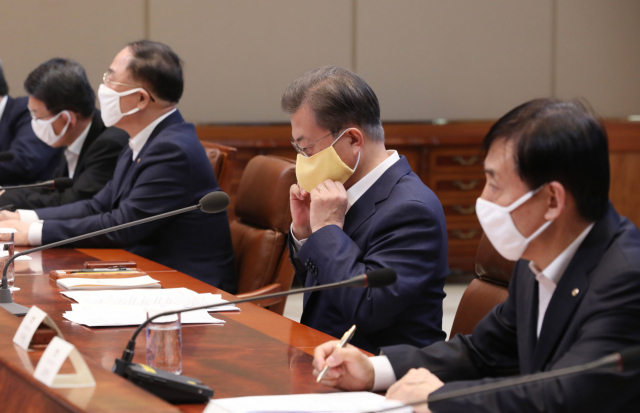 문재인 대통령이 19일 청와대에서 열린 코로나19 대응 논의를 위한 비상경제회의에서 발언을 마친 뒤 마스크를 다시 쓰고 있다. 연합뉴스